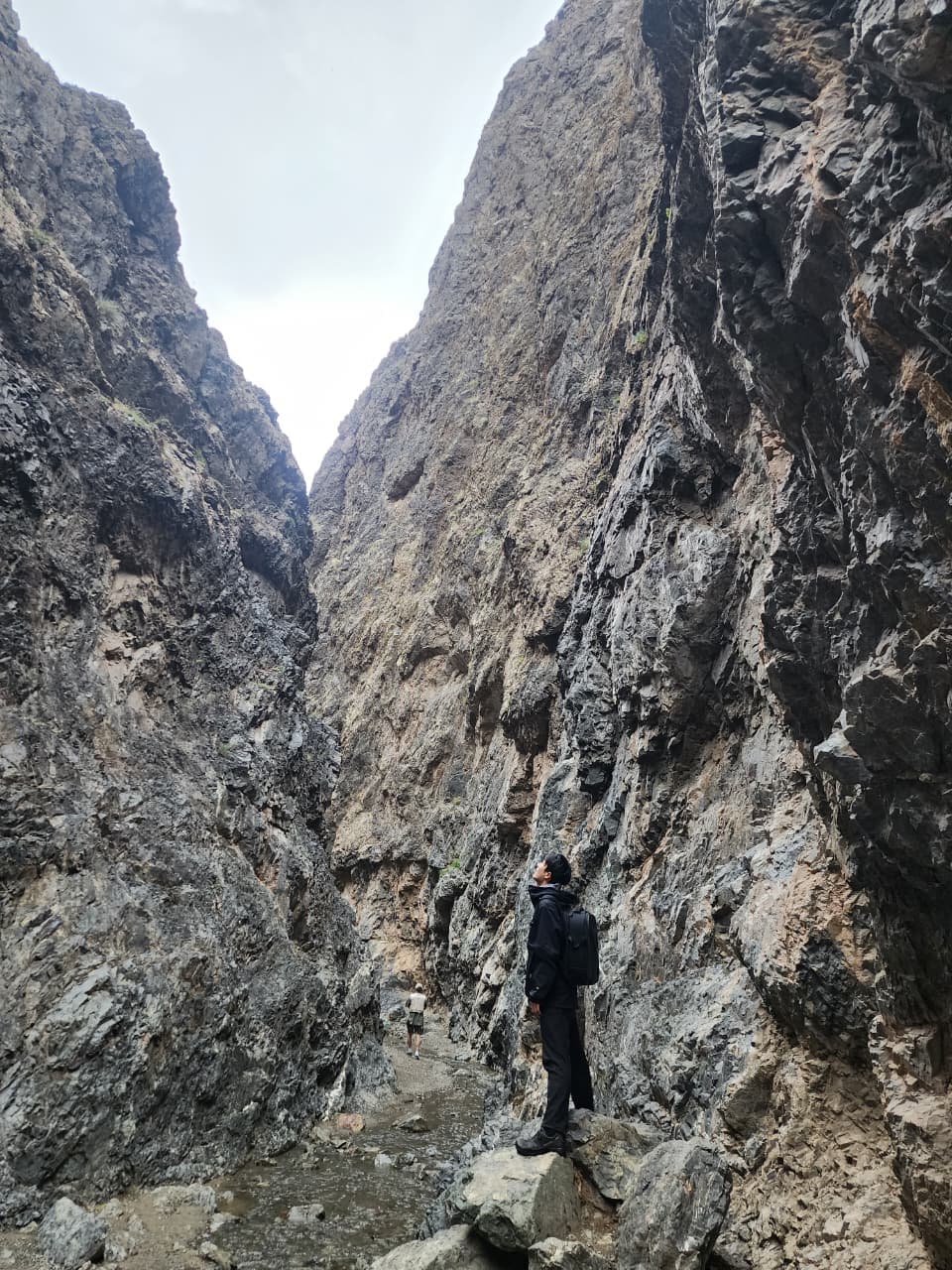 Hikers walking through the Yol Valley ice canyon